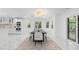 Bright dining room with a black table, white chairs, modern lighting, and a view to the kitchen at 305 Sweetwater Club Cir, Longwood, FL 32779