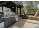 Outdoor kitchen with grill, sink, tiled backsplash, and views of the surrounding trees at 305 Sweetwater Club Cir, Longwood, FL 32779