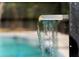 Close-up of a modern waterfall feature cascading into the sparkling swimming pool at 305 Sweetwater Club Cir, Longwood, FL 32779