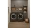 Well-organized laundry room with gray cabinetry, shelving, and front-loading washer and dryer units at 3553 Sw 157Th Loop, Ocala, FL 34473