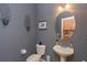 Stylish half bath with pedestal sink, oval mirror, and decorative wall art at 11314 Ledgement Ln, Windermere, FL 34786