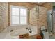 A soaking tub sits below a window with a stone accent wall and glass enclosed shower at 11314 Ledgement Ln, Windermere, FL 34786
