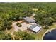 Lush aerial view of estate featuring mature trees, a pool, a pond, and a custom home with unique parking at 11450 Nellie Oaks Bnd, Clermont, FL 34711