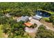 Wide aerial view of estate featuring a pond, lush landscaping, and custom home with a unique layout and covered parking at 11450 Nellie Oaks Bnd, Clermont, FL 34711
