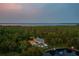 An aerial view of an estate with a beautiful surrounding forest and lake at twilight at 11450 Nellie Oaks Bnd, Clermont, FL 34711