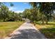 Long private driveway leading to the main house, enhanced with mature trees and manicured lawns at 11450 Nellie Oaks Bnd, Clermont, FL 34711