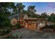 Elegant home at dusk, featuring a porte cochere, lush landscaping, and stately palm trees at 11450 Nellie Oaks Bnd, Clermont, FL 34711