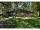 View of the exterior of the property with an enclosed pool area and lots of trees at 11450 Nellie Oaks Bnd, Clermont, FL 34711