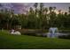 Scenic pond view featuring a fountain, swan boat, and gazebo against a backdrop of lush trees and a tranquil sunset sky at 11450 Nellie Oaks Bnd, Clermont, FL 34711