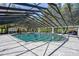A stunning covered pool with ample patio space surrounded by lush trees and a glimpse of the blue sky at 11450 Nellie Oaks Bnd, Clermont, FL 34711