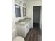Modern bathroom with double vanity, granite countertops, wood-look flooring, and white cabinets at 13075 Se 35Th Ct, Belleview, FL 34420