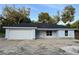 Single-story home with a two-car garage, light blue exterior, modern windows, and simple landscaping at 13075 Se 35Th Ct, Belleview, FL 34420