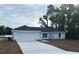 Charming light blue single-story home with a gray roof, attached garage, and freshly laid sod in the front yard at 13075 Se 35Th Ct, Belleview, FL 34420