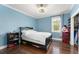 A blue bedroom with dark hardwood floors, a fan, and a black bed frame at 17726 Dangler Rd, Winter Garden, FL 34787