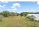 A large green field is surrounded by mature trees under a cloudy, blue sky at 17726 Dangler Rd, Winter Garden, FL 34787