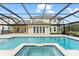 Screened pool with in-ground spa and sun shelf, framed by a neutral colored stone deck at 17726 Dangler Rd, Winter Garden, FL 34787