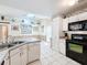 Kitchen showcasing white cabinets and black appliances, with tile flooring throughout at 2617 Greywall Ave, Ocoee, FL 34761