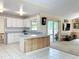 Kitchen area with an island with wood paneling, opening up to a carpeted living room at 2617 Greywall Ave, Ocoee, FL 34761