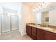 Well-lit bathroom featuring double sinks, granite countertops, and a glass-enclosed shower at 291 Pendant Ct, Kissimmee, FL 34747