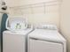 Functional laundry room with washer, dryer, ironing board, wire shelving and white plastic laundry basket at 291 Pendant Ct, Kissimmee, FL 34747