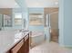 Bright bathroom featuring double windows, vanity, soaking tub, and glass shower at 4918 Oakway Dr, St Cloud, FL 34771
