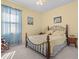 Comfortable bedroom with carpet floors, a ceiling fan, a window with blue curtains, and a wrought iron bed frame at 4918 Oakway Dr, St Cloud, FL 34771