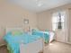 Bright bedroom featuring two twin beds with blue comforters, a ceiling fan, and a window at 4918 Oakway Dr, St Cloud, FL 34771
