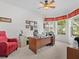 Bright office space with large windows, a ceiling fan, and a cozy red chair at 4918 Oakway Dr, St Cloud, FL 34771