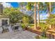 Landscaped backyard with a lake view, featuring a stone patio with an outdoor dining set and mature trees at 6082 Twin Lakes Dr, Oviedo, FL 32765