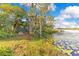 Lakefront backyard featuring a small bench and a wooden dock by the water's edge surrounded by lush trees at 6082 Twin Lakes Dr, Oviedo, FL 32765