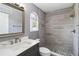 Updated bathroom features gray tiling, a stylish vanity and mirror, and a window for natural light at 6761 Scimitar Ave, Orlando, FL 32812