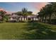 Elegant two-story home with a manicured lawn and mature palm trees, showcasing its curb appeal under a colorful sky at 6761 Scimitar Ave, Orlando, FL 32812