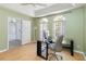 Bright office space featuring hardwood floors, two arched windows, and a modern black desk with glass top at 6761 Scimitar Ave, Orlando, FL 32812