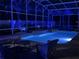 Private screened-in pool with spillover spa, enhanced by vibrant blue nighttime lighting at 6761 Scimitar Ave, Orlando, FL 32812