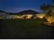Nighttime view of the sprawling backyard, featuring tasteful landscape lighting and manicured lawn at 8225 Corkfield Ave, Orlando, FL 32832