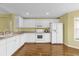 Well-lit kitchen with white appliances and cabinetry, complete with wood-look flooring at 8602 Se 133Rd Ln, Summerfield, FL 34491