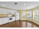 Sunlit kitchen with white appliances, cabinets and wood-look flooring with multiple windows at 8602 Se 133Rd Ln, Summerfield, FL 34491
