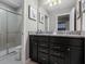 Bathroom featuring granite counters, dark cabinetry, and a glass-enclosed shower at 8892 Bengal Ct, Kissimmee, FL 34747