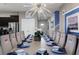 A spacious dining room featuring a large table set with blue and white dinnerware and a modern chandelier at 8892 Bengal Ct, Kissimmee, FL 34747