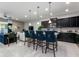 Kitchen bar with four blue bar stools, view into the living room, and dark cabinets in the kitchen at 8892 Bengal Ct, Kissimmee, FL 34747