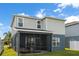 View of the back exterior of a home featuring a screened-in porch and green lawn at 903 Sydney St, Davenport, FL 33837