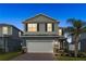 Two-story home with manicured lawn, garage, and lush tropical landscaping at 903 Sydney St, Davenport, FL 33837