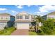 Charming two-story home featuring a brick driveway, two car garage and tropical landscaping at 903 Sydney St, Davenport, FL 33837