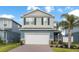 Two-story home with a brick driveway, attached garage, and tropical landscaping at 903 Sydney St, Davenport, FL 33837