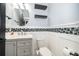 Stylish bathroom with vanity, round mirror, decorative wall tiles, floating shelves, and white toilet at 9330 Meadow Hunt Way, Winter Garden, FL 34787