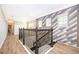 Bright hallway with unique accent wall, wood floors, iron railing, and recessed lighting at 9330 Meadow Hunt Way, Winter Garden, FL 34787