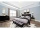 Beautiful main bedroom featuring a luxurious bed, and large windows with grey accent draperies at 9330 Meadow Hunt Way, Winter Garden, FL 34787