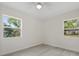A bright, empty bedroom features two large windows, light gray floors, and white walls for customization at 239 S Lake Cortez Dr, Apopka, FL 32703