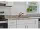 Close-up of kitchen with granite countertops, white cabinets, stainless steel faucet, and modern appliances at 239 S Lake Cortez Dr, Apopka, FL 32703