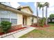 View of a charming one-story home featuring a well-maintained lawn with trees, and yellow siding at 321 Moffat Loop, Oviedo, FL 32765